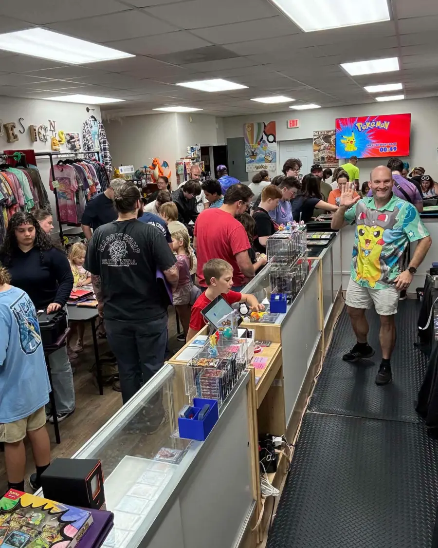 A packed PokeShop 850 with shoppers along the glass counters and a staff member waving