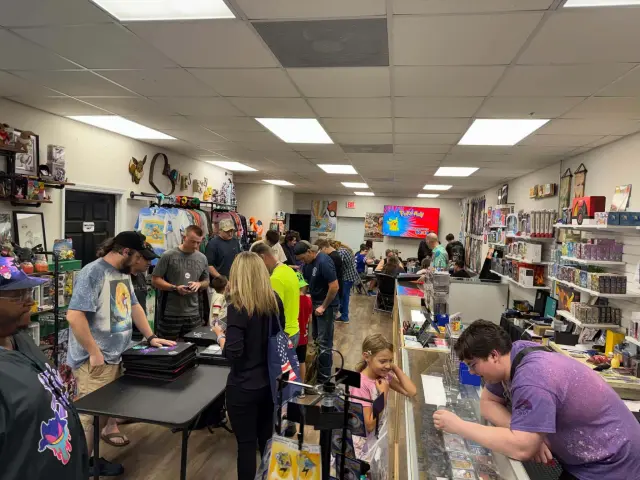 Collectors browsing binders and the display case inside the shop
